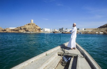 Téléchargez les photos : Sur, Oman - 1er juin 1996 : homme de ferry arabe sur son bateau en bois à Sur, Oman. - en image libre de droit