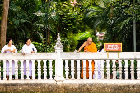 Téléchargez les photos : Bangkok, Thaïlande - 26 décembre 2007 : Des femmes vêtues de blanc et des moines habillés en orange jettent des blossons dans la rivière pour honorer la divinité - en image libre de droit