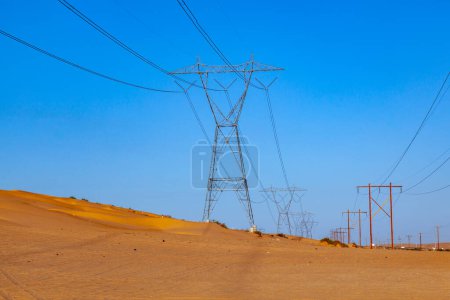 Photo for Electric pylon in the desert with wooden pile under blue sky - Royalty Free Image
