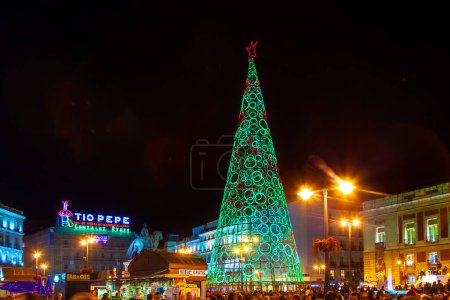 Photo for Madrid, Spain - December 22, 2010:  People have fun in Christmas time passing the famous illuminated christmas tree at puerta del sol in Madrid, Spain. - Royalty Free Image