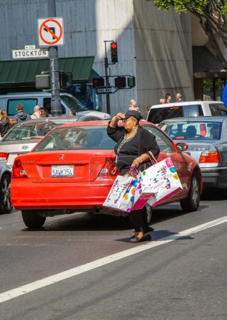 Photo for San Francisco, USA - July 24, 2008: woman with fully filled shopping bag crosses a street downtown San Francisco after shopping. - Royalty Free Image