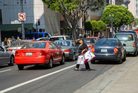 Photo for San Francisco, USA - July 24, 2008: woman with fully filled shopping bag crosses a street downtown San Francisco after shopping. - Royalty Free Image