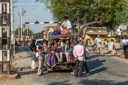 Foto de Fathepur Sikri, India - 16 de noviembre de 2011: personas en un mini autobús sobrecargado o rickshaw esperando en una cola para el tren que pasa.. - Imagen libre de derechos