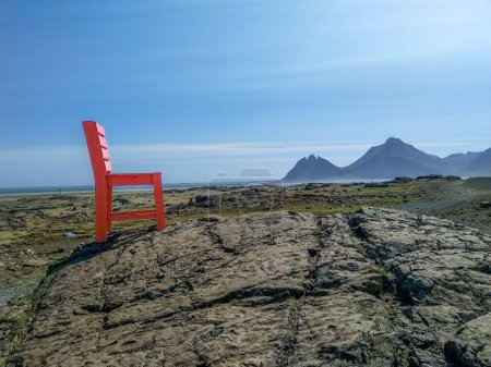 Herrlicher sonniger Tag und roter Holzstuhl zwischen Höfen und Egilsstadir in Island. Standort stokksnes cape, Island, Europa.
