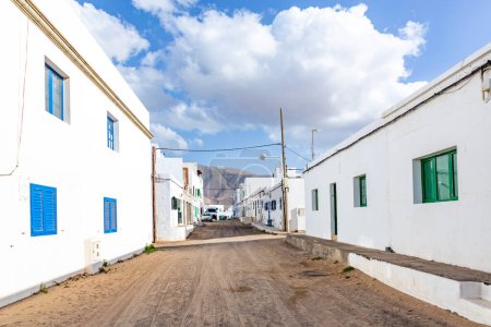 Photo for Scenic row of white panited houses with sandy road in Famara, Lanzarote - Royalty Free Image