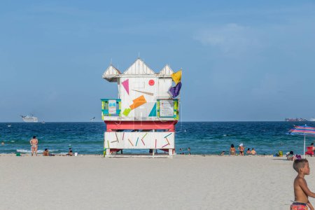 Photo for Miami, USA - August 18, 2014: People at the sea side in Miami with lifeguard tower, USA. Miami Beach is a popular destination among tourists, spiking during the winter time. - Royalty Free Image