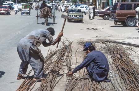 Foto de Peshawar, Pakistán - 30 de junio de 1987: trabajadores de la calle preparan barras de hierro para formar una rejilla para la estabilización del yeso. - Imagen libre de derechos