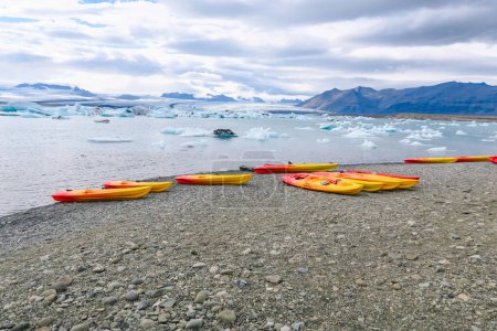 Photo for The joekulsar lagoon with icebergs  and eroding glacier in Iceland and empty canoes at the beach for rent - Royalty Free Image