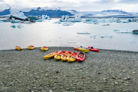 Photo for The joekulsar lagoon with icebergs  and eroding glacier in Iceland and empty canoes at the beach for rent - Royalty Free Image