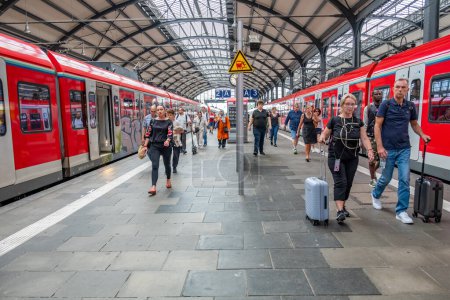 Foto de Wiesbaden, Alemania - 16 de agosto de 2023: la gente espera en la estación de tren la salida en la estación de tren clasicista de Wiesbaden, la copia más pequeña de la estación de tren de Frankfurt. - Imagen libre de derechos