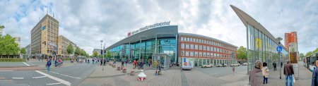 Foto de Muenster, Alemania - 5 de agosto de 2023: la gente se apresura a llegar a la estación de tren con su moderna construcción de fachadas de vidrio en Munster, Alemania. - Imagen libre de derechos