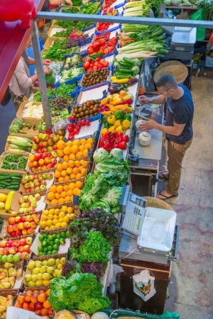 Foto de Frankfurt, Alemania - 9 de agosto de 2014: el hombre vende verduras y frutas frescas en el Kleinmarkthalle - engl: small markethall - en Frankfurt. - Imagen libre de derechos
