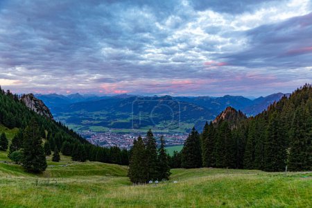 Téléchargez les photos : Lever de soleil vu du sommet de la montagne de Gruenten avec village de Rettenberg et panorama des Alpes, Allemagne - en image libre de droit