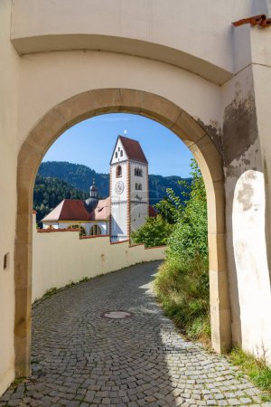 Foto de Vista de la famosa e increíble iglesia de Fussen a través de la puerta principal del castillo con cielo azul, Alemania - Imagen libre de derechos