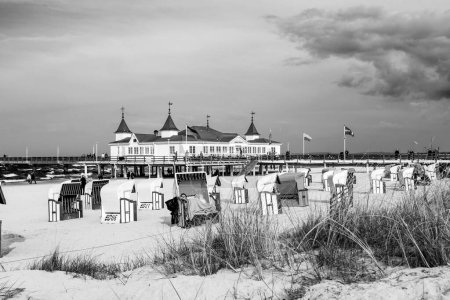 Téléchargez les photos : AHLBECK, ALLEMAGNE - 20 AVRIL 2014 : les gens apprécient la jetée et la plage d'Ahlbeck, en Allemagne. La mer Baltique dans l'île d'Usedom est célèbre pour ses chaises de plage en osier toiture unique
. - en image libre de droit