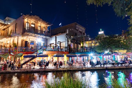 Foto de San Antonio, Estados Unidos - 31 de octubre de 2023: la gente disfruta de la noche en el Paseo del Río San Antonio con disfraces por la noche y árboles y restaurantes iluminados. - Imagen libre de derechos
