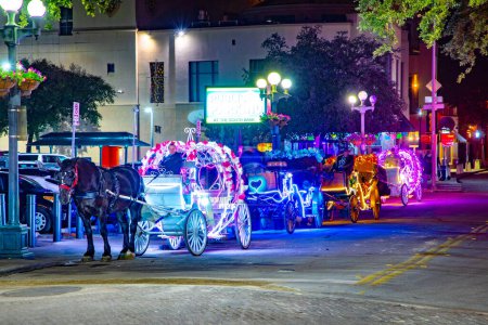 Foto de San Antonio, Estados Unidos - 31 de octubre de 2023: la gente disfruta de un paseo nocturno en el carruaje tirado por caballos con luz de neón colorida en San Antonio en la zona de paseo del río. - Imagen libre de derechos