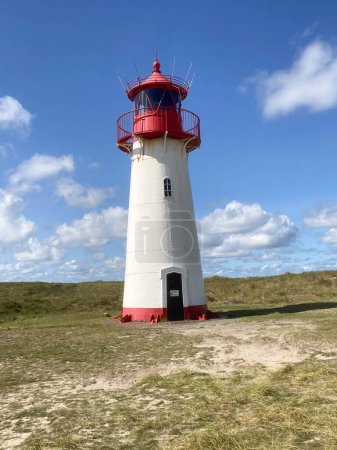 Téléchargez les photos : Phare sur dune de sable contre ciel bleu avec nuages blancs sur la côte nord de l'île de Sylt près de List village, Allemagne - en image libre de droit