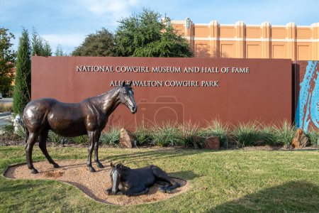 Téléchargez les photos : Fort Worth, Texas - 5 novembre 2023 : vue extérieure sur le musée des cow-girls et le temple de la renommée avec deux chevaux bruns à l'herbe. - en image libre de droit