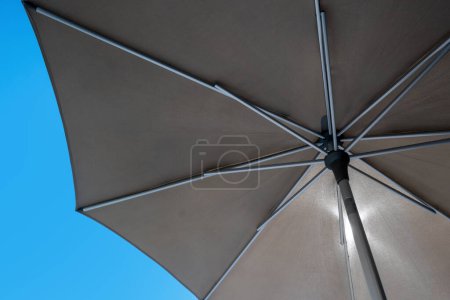 Téléchargez les photos : Détail de parapluie brun avec ciel bleu clair en arrière-plan comme symbole de voyage - en image libre de droit