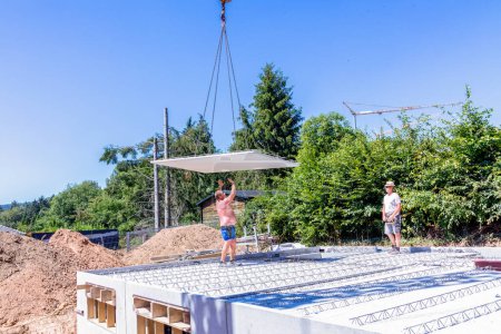 Téléchargez les photos : Fischbach, Allemagne - 31 juillet 2020 : le travailleur met en œuvre le plafond de la cave ou la plaque de plancher en béton sur un nouveau chantier de construction de maison familiale. - en image libre de droit