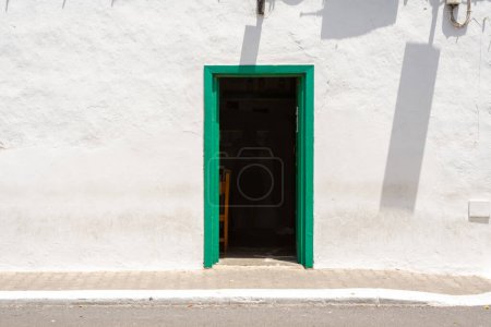 Foto de Patrón de pared blanca rural con marco típico de madera verde puerta y sombra en Lanzarote - Imagen libre de derechos
