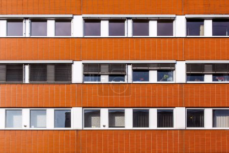 fachada de una casa de oficinas con pared roja y ventanas de área de trabajo
