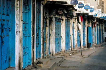 Photo for Sanaa, Yemen - July 1, 1991: closed shops in Sanaa with typical blue doors all with advertising for the cigatette brand Rothmans. - Royalty Free Image