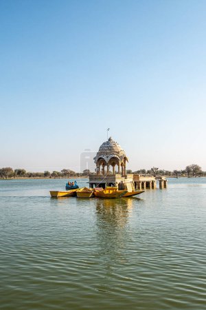 Photo for Jaisalmer, India - February 12, 2024: people visit by boat the Gadsisar Sagar Lake with historic buildings to store rainwater and ensure a steady water supply for the city of Jaisalmer, India. - Royalty Free Image