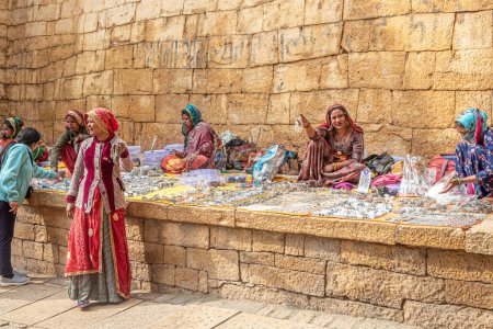 Téléchargez les photos : Jaisalmer, Inde - février 13, 2024 : les femmes en vêtements traditionnels vendant des souvenirs faits maison comme des colliers, des anneaux, des perles, de petites choses assis le fort Jaisalmer, Rajasthan, Inde. - en image libre de droit