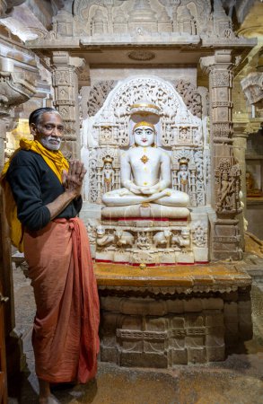 Photo for Jaisalmer, India - February 12, 2024: praying man in front of a buhhda statue Chandraprabha or Lord of Moon at the Jain temple in Jaisalmer, India. - Royalty Free Image