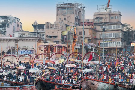Téléchargez les photos : Varanasi, Inde - 24 février 2024 : vieux bateaux en bois à la jetée à la frontière de Rriver Ganges dans la lumière du matin avec beaucoup de gens à la jetée et sur les bateaux. - en image libre de droit