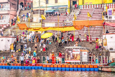 Photo for Varanasi, India - February 24, 2024: boats at the gaths in morning lighrt with people follow their deat cult procession at the border of holy river ganges in Varanasi. - Royalty Free Image