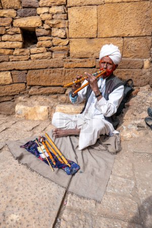 Photo for Jaisalmer, India - February 13, 2024: flute playing old man begging for alms at the Jaisalmer Fort, Rajasthan, India. - Royalty Free Image
