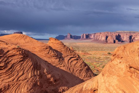 A hike into a remote area of Monument Valley Arizona during dusk shows a beautiful expanse framed by erosion patterns that were formed in the sandstone by water and wind over millions of years.