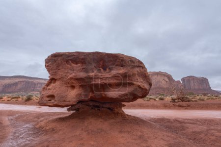 A large hoodoo formation along a dirt road in Monument Valley shows millions of years of erosion caused by water and wind.