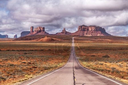 View of Forrest Gump Scenic road in Monument Valley, Utah during a cloudy day shows the long, lonely road moving into Arizona through the famous mountain range shown in the movie.