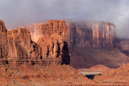 Large mountain along the side of Monument Valley's scenic park during a gloomy day shows the rock patterns, generally made of sandstone, moenkopi and or shinarump rock.