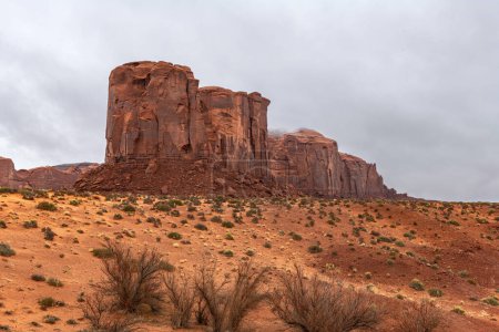 Gran montaña a lo largo del lado del parque escénico de Monument Valley durante un día nublado muestra los patrones rocosos, generalmente hechos de piedra arenisca, moenkopi y o roca shinarump.