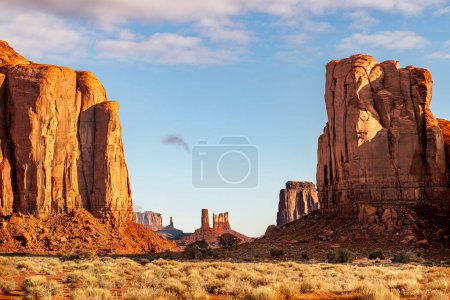 Mountainside lit up by a rising sun casts an orange color against the landscape in Monument Valley, Arizona, a southwest destination for adventure seekers.