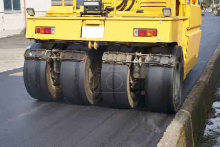 Photo for Pneumatic roller of tires compacting new asphalt of a street. Repaving the road surface. Road works - Royalty Free Image