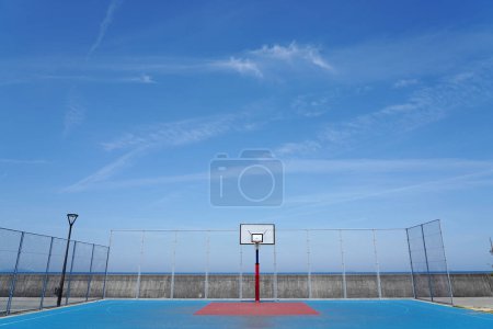 Téléchargez les photos : Basketball cerceau sur un terrain extérieur vide sur un ciel bleu. - en image libre de droit