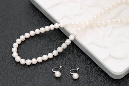 Foto de Elegante collar de perlas blancas y pendientes sobre fondo negro - Imagen libre de derechos