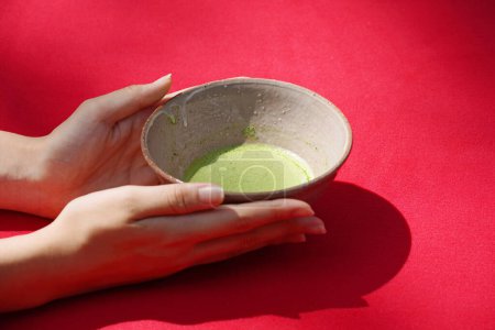Photo for Young woman's hand holding traditional Japanese green tea bowl (Macha). - Royalty Free Image