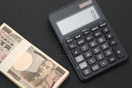 Photo for Japanese salary envelope and calculator, The banknotes are written as "10,000 yen" in Japanese. - Royalty Free Image