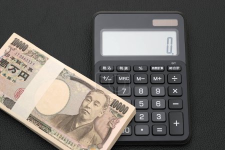 Foto de Sobre y calculadora salarial japonesa, Los billetes se escriben como "10.000 yenes" en japonés. - Imagen libre de derechos