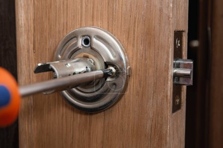 Photo for Locksmith carpenter fix knob on wooden door by screwdriver for home service reparation - Royalty Free Image