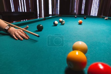 Foto de Player holding que and aiming to billiard white ball. White ball on gree poll table - Imagen libre de derechos