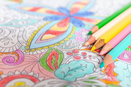 Colored mandala coloring book with pencils implies mindfulness. Mental health and creativity content