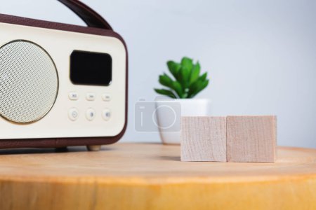 Altes Radio und kleine Topfpflanze auf einem Holztisch mit zwei Holzklötzen, Morgenroutine und Nachrichten